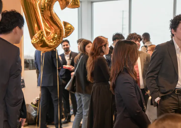 Students standing in conversation, a large gold balloon letter above them.