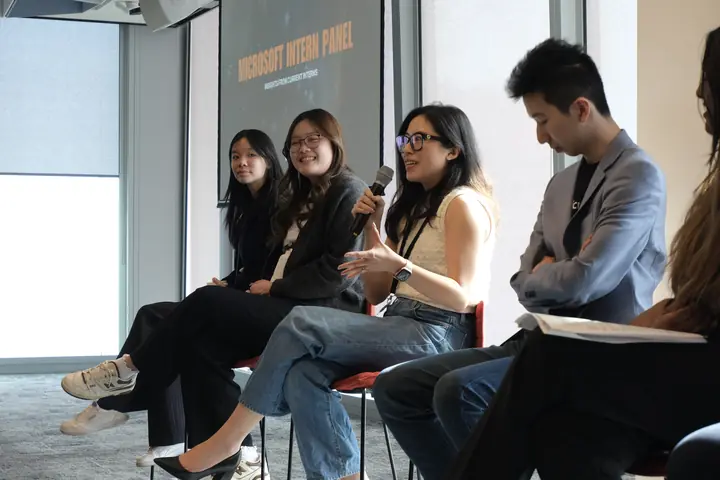 Four panellists on stools, one speaking into a microphone.