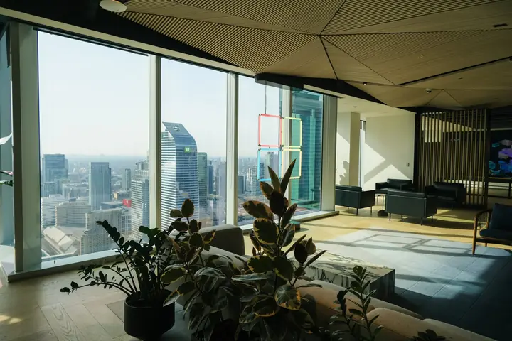 An empty lounge with a timber ceiling, plants and floor-to-ceiling glass.