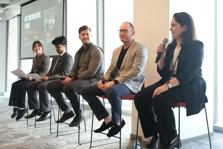 Five panellists on stools with microphones.